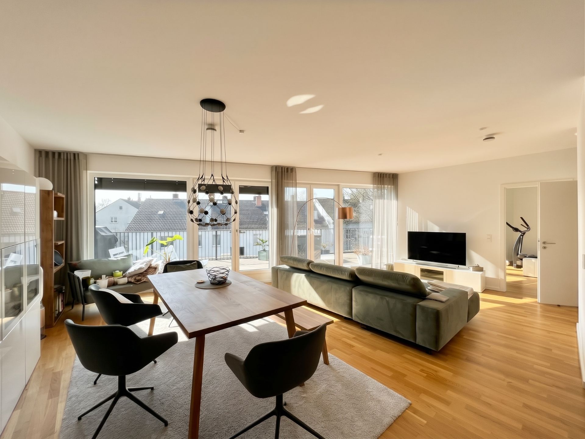 Modernes Wohnzimmer mit Esstisch, Sofa, Fernseher und großen Fenstern zur Terrasse.