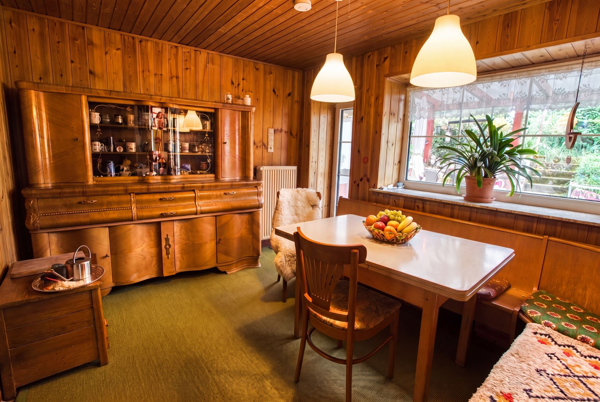 Gemütliches Esszimmer mit Holzmöbeln, großem Fenster, Esstisch und Obstschale.