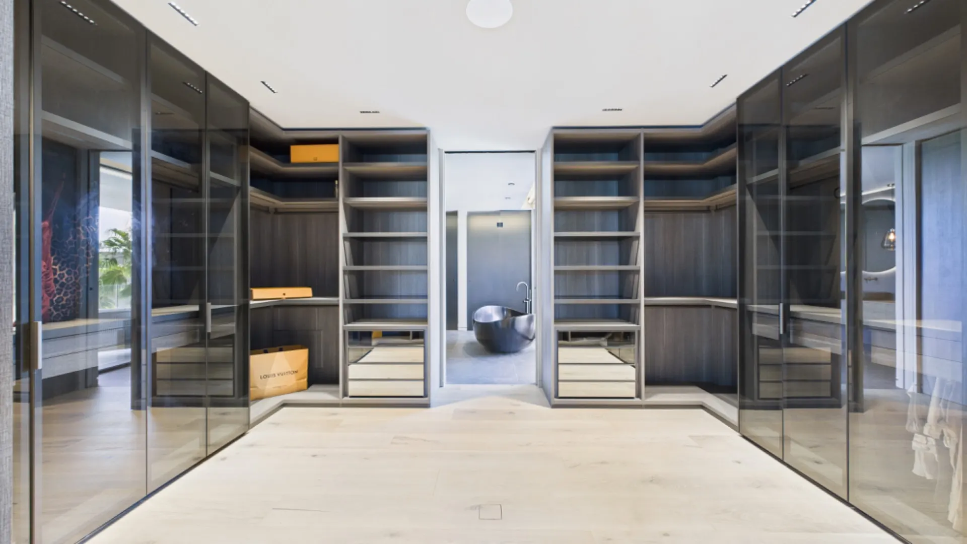 Großer, moderner begehbarer Kleiderschrank mit Glasfronten und offenen Regalen.