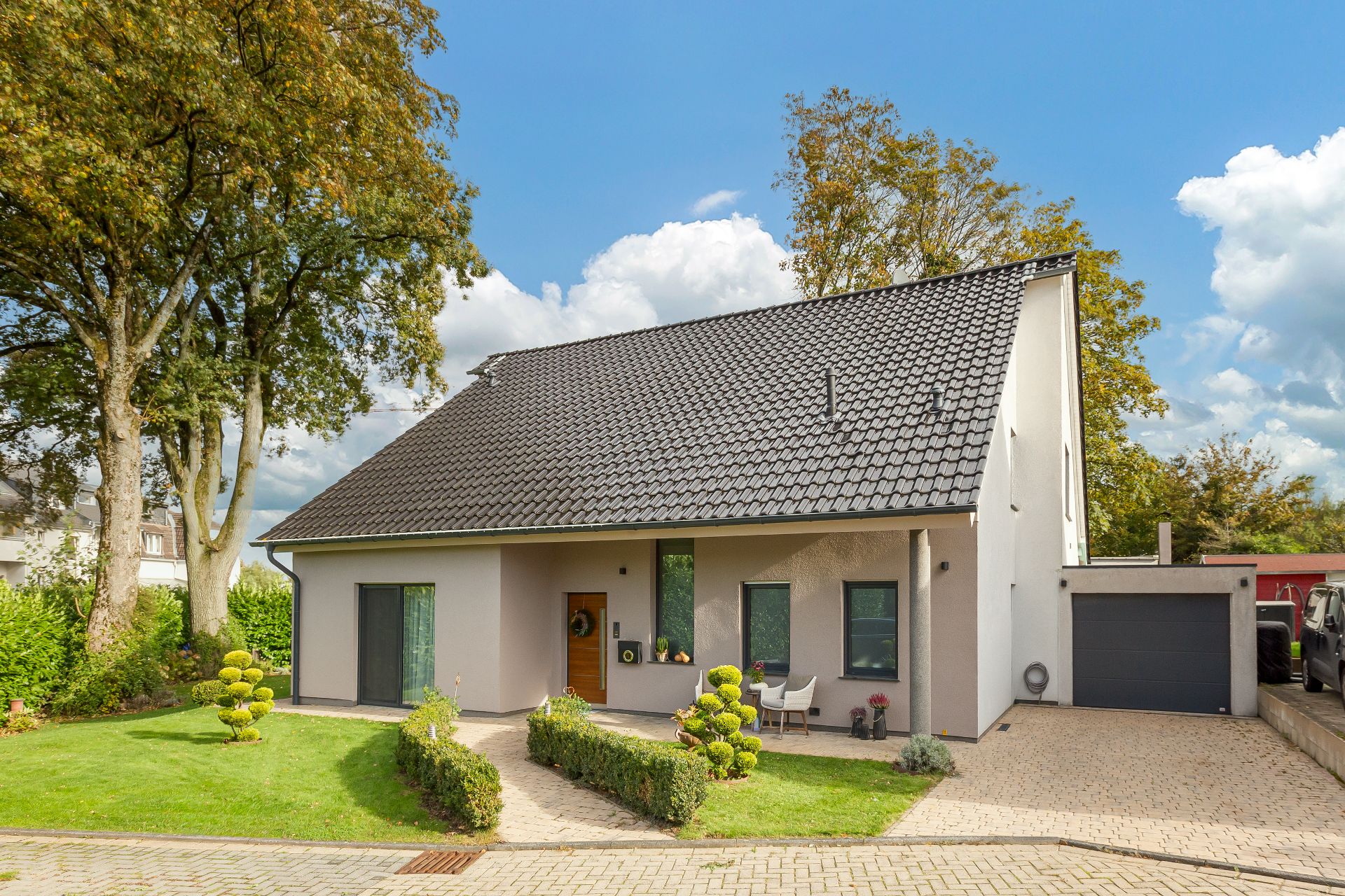 Modernes Einfamilienhaus mit schrägem Dach, Vorgarten und Einfahrt mit Garage.