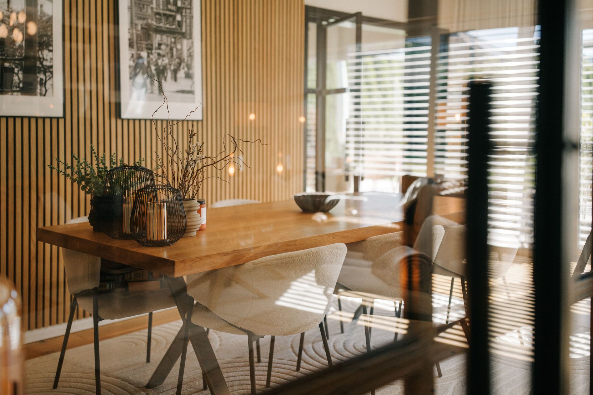 Esszimmer mit Holztisch, sechs Stühlen und Dekoration, an einer Wand mit Holzpaneelen und Bildern.
