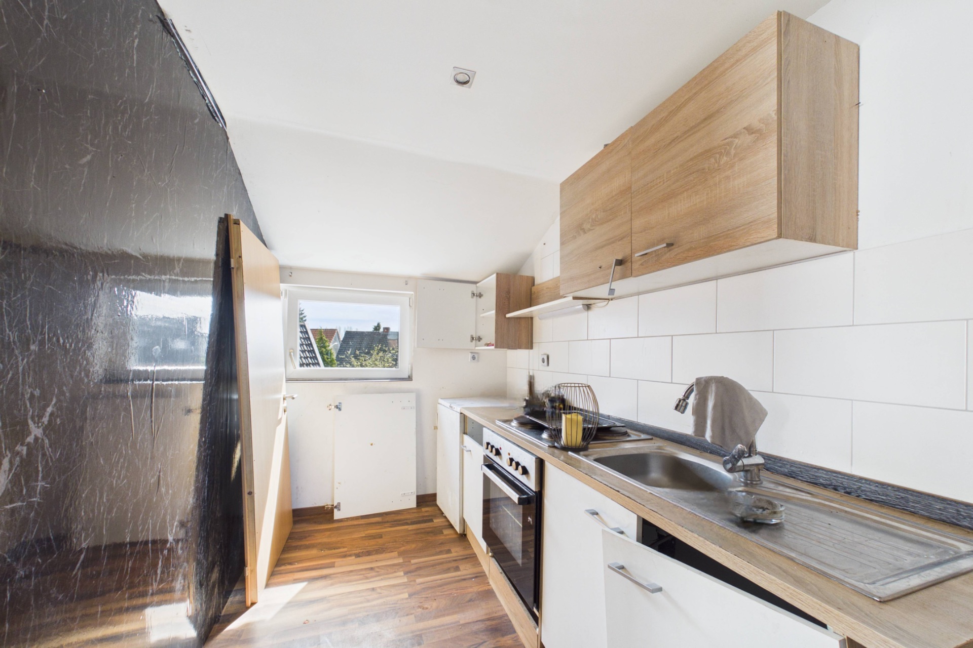 Helle Küche mit Holzschränken, Fenster, Herd und Spüle.