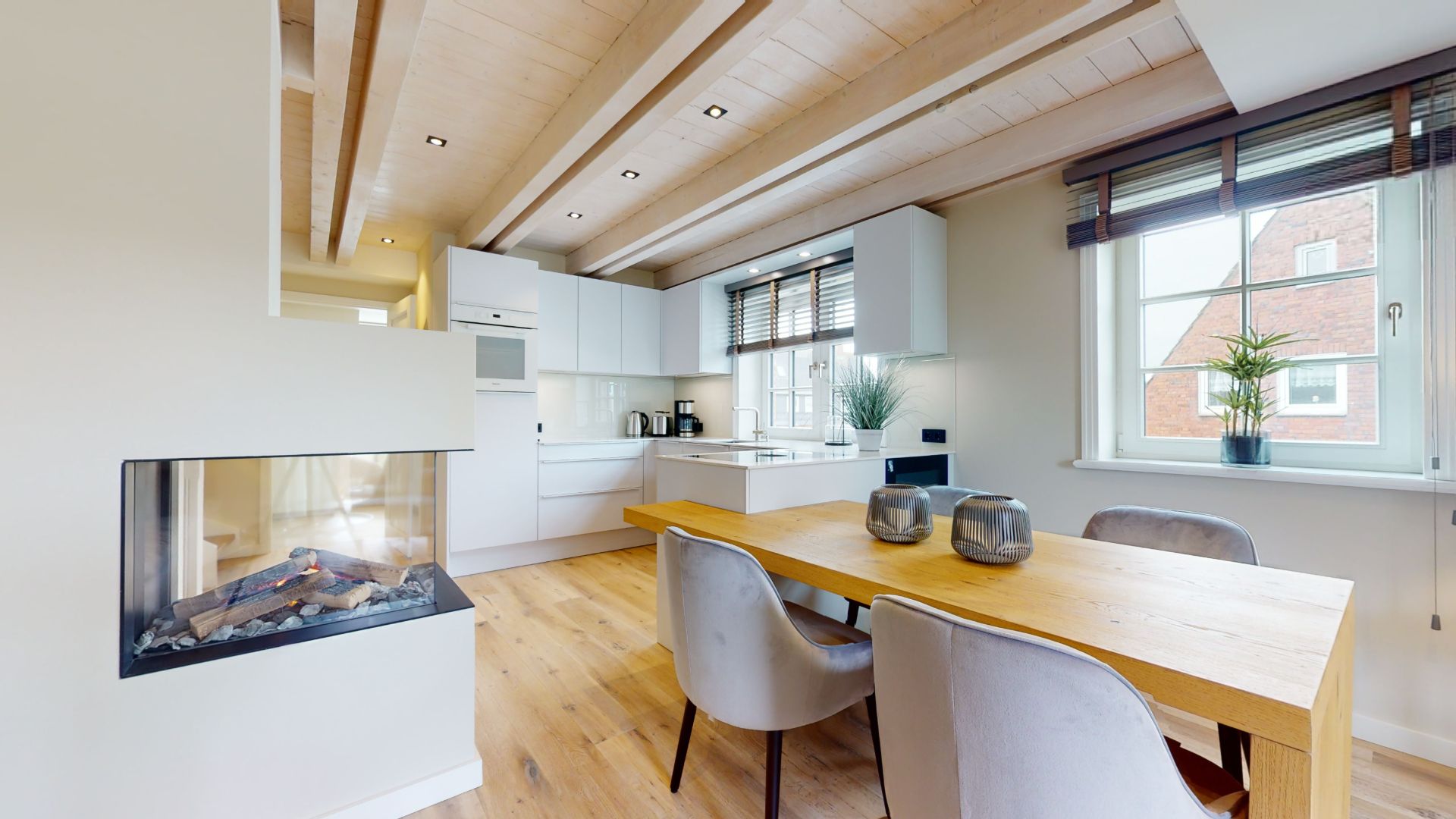 Moderne Küche mit Essbereich, Holzboden, Kamin und großem Fenster mit Pflanzen.