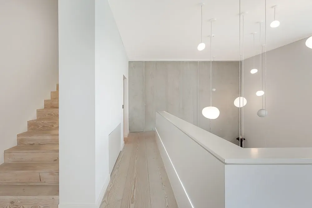 Helle Holztreppe und Flur mit modernen Hängelampen in einem Wohnhaus.