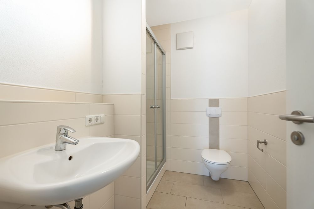 Modernes Badezimmer mit Waschbecken, Dusche und Wandtoilette.