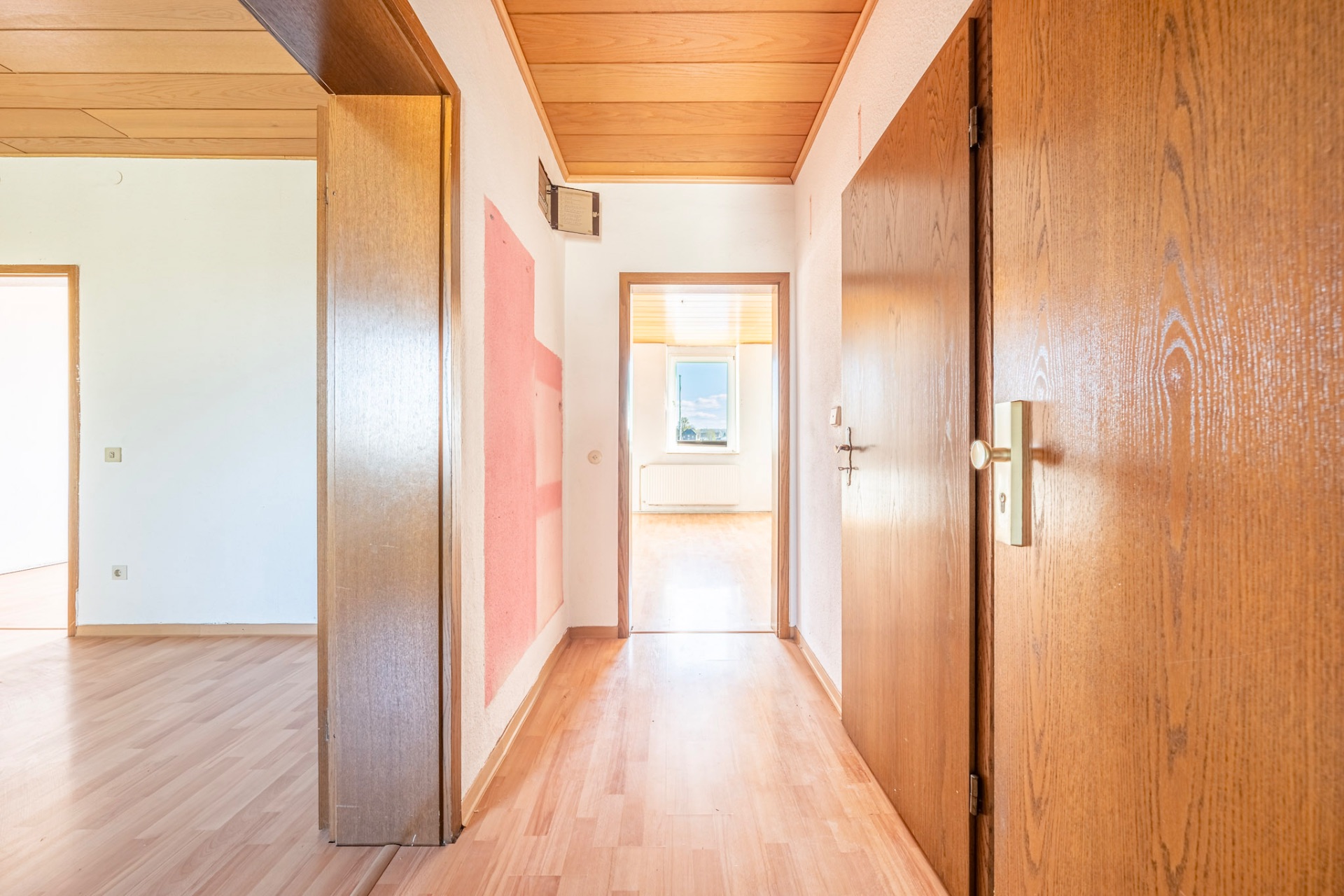 Heller Flur mit Holztüren und Laminatboden in einer Wohnung.