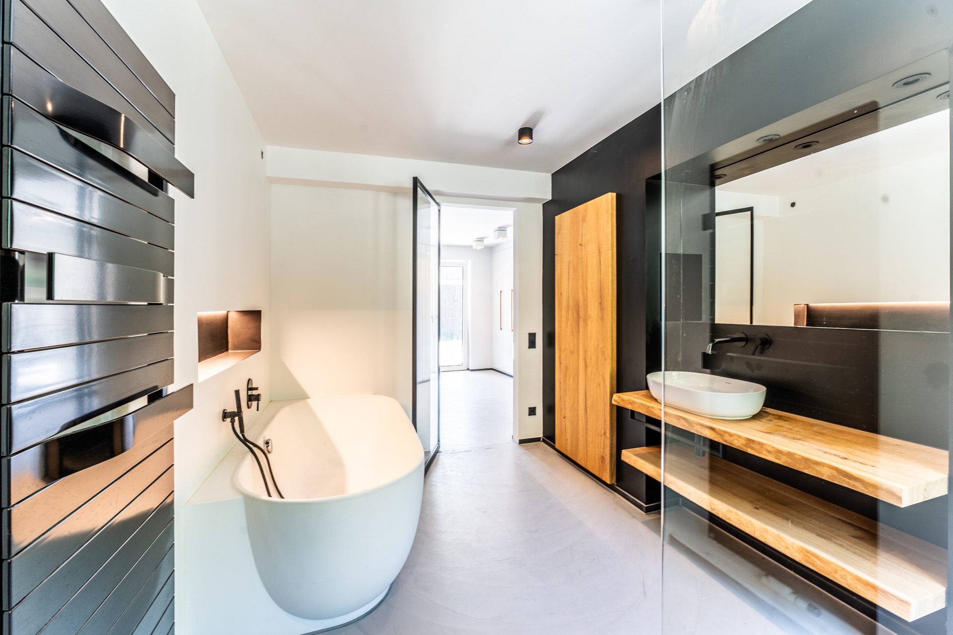 Modernes Badezimmer mit freistehender Badewanne, Holzwaschtisch und großem Spiegel.