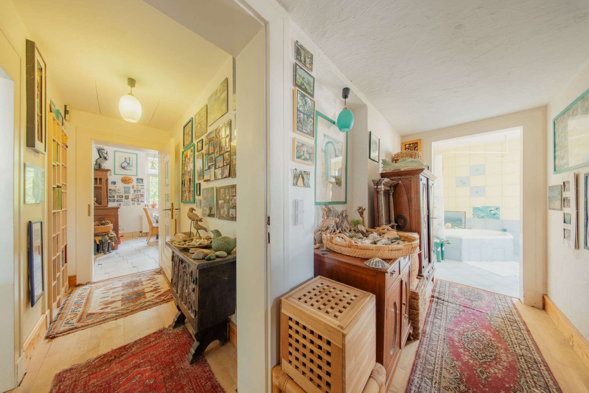 Heller Flur mit Holzmöbeln, Teppichen und Wanddekorationen in einem Wohnhaus.