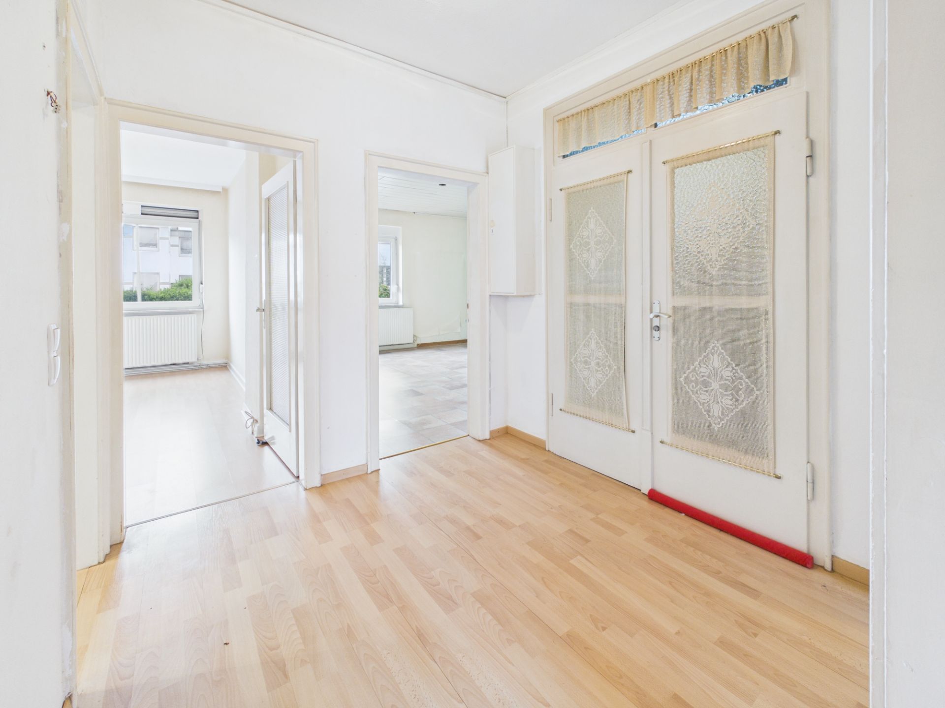 Heller Flur mit Holzboden, zwei Türen mit Glas und Blick in zwei weitere Zimmer.