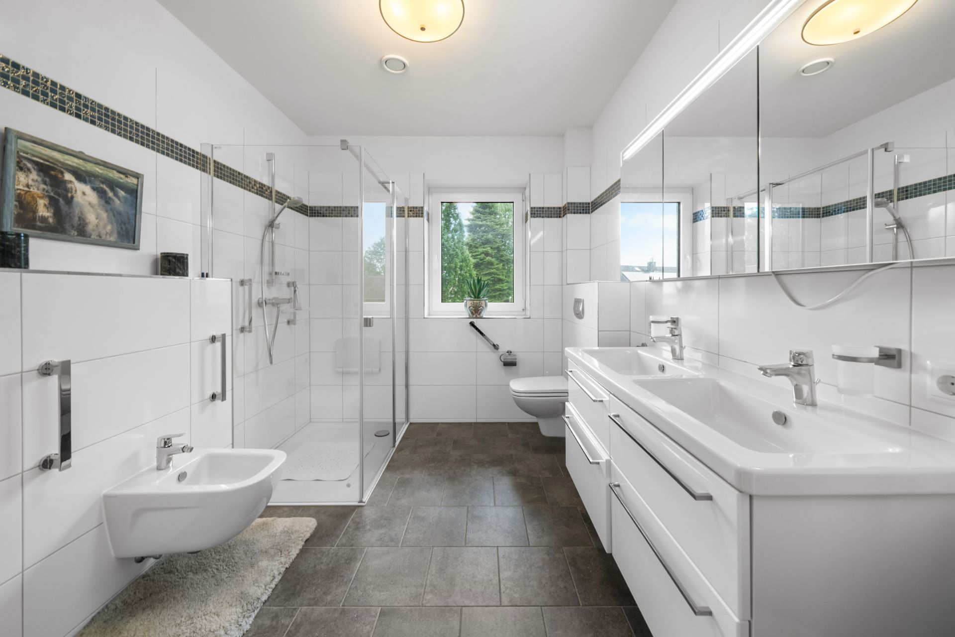 Modernes Badezimmer mit Doppelwaschbecken, Dusche, WC, Bidet und Fenster.