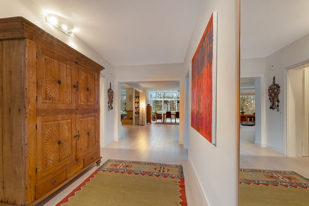 Heller Flur mit großem Holzschrank, Teppich, Wandbild und Blick ins Wohnzimmer.