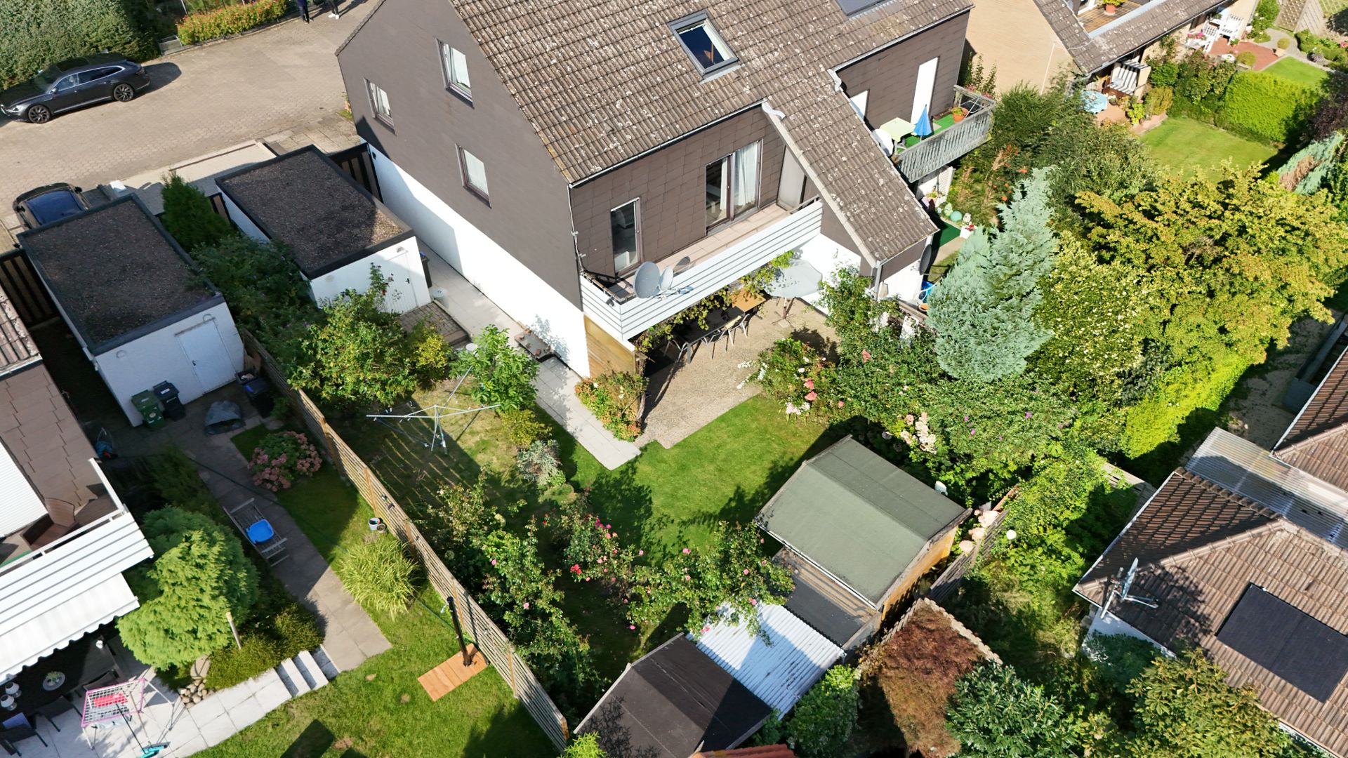 Luftaufnahme eines Wohnhauses mit Garten, Terrasse und mehreren Bäumen.