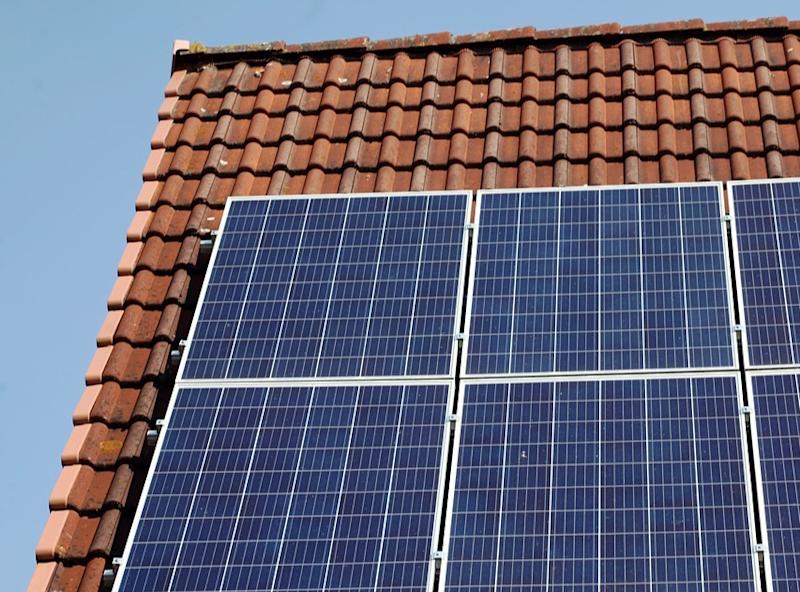 Vier Solarpanels auf einem roten Ziegeldach bei klarem Himmel.