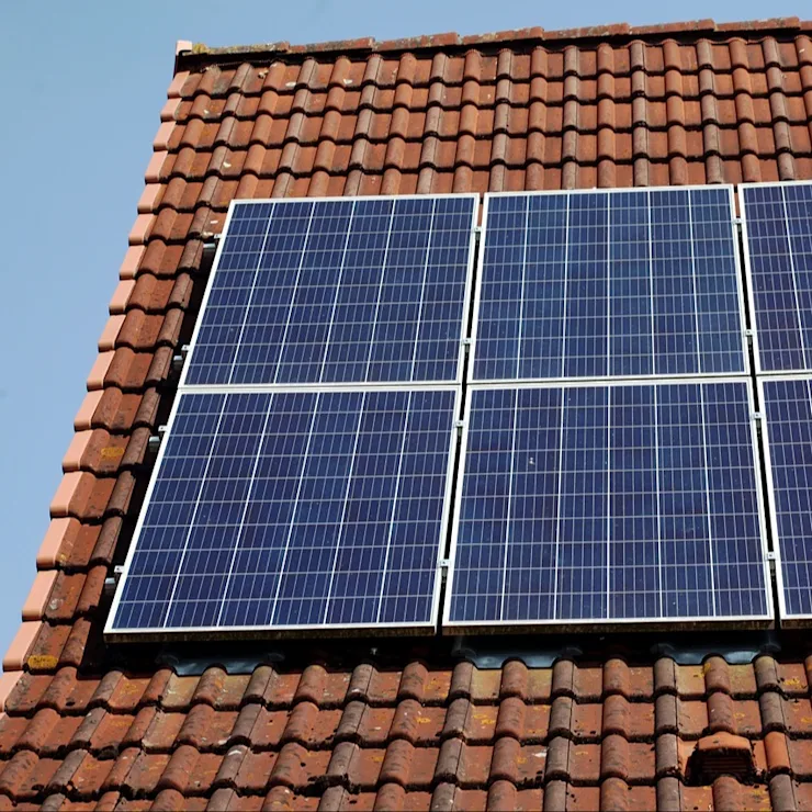 Vier Solarpanels auf einem roten Ziegeldach bei klarem Himmel.