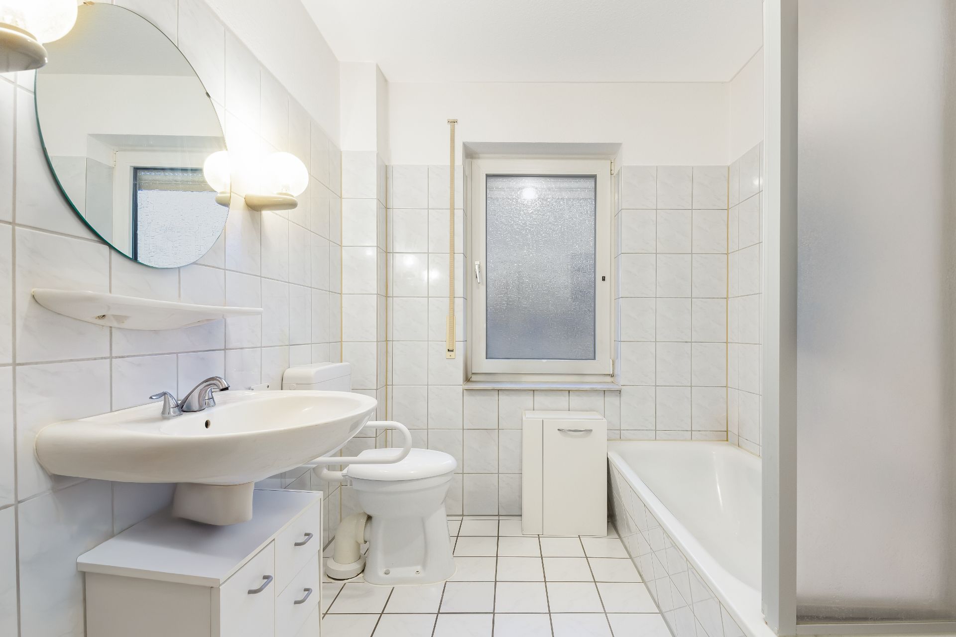 Helles Badezimmer mit Waschbecken, Toilette, Badewanne, Dusche und Fenster.