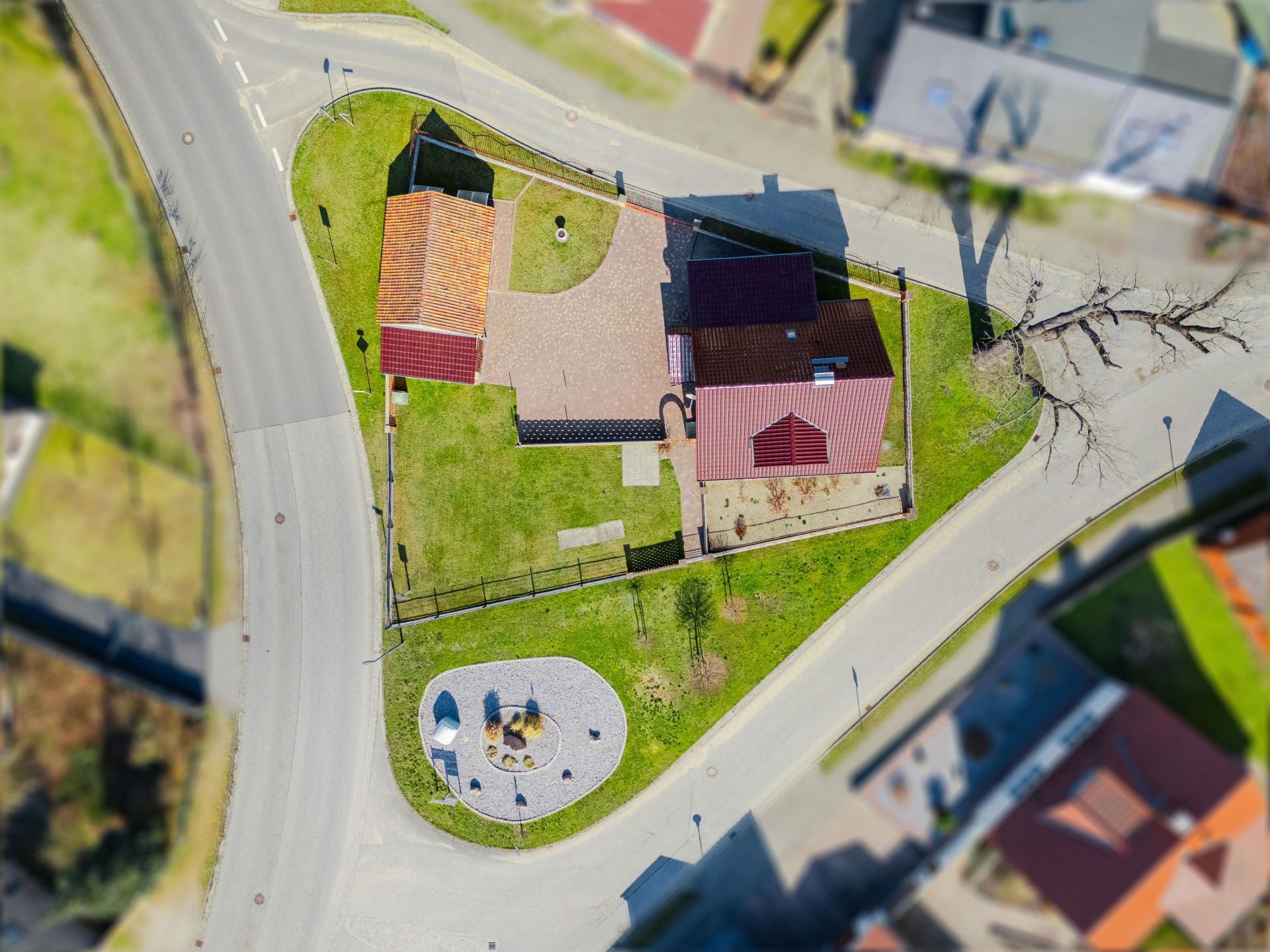 Luftaufnahme eines Hauses mit rotem Dach, Garten und umliegender Straße.