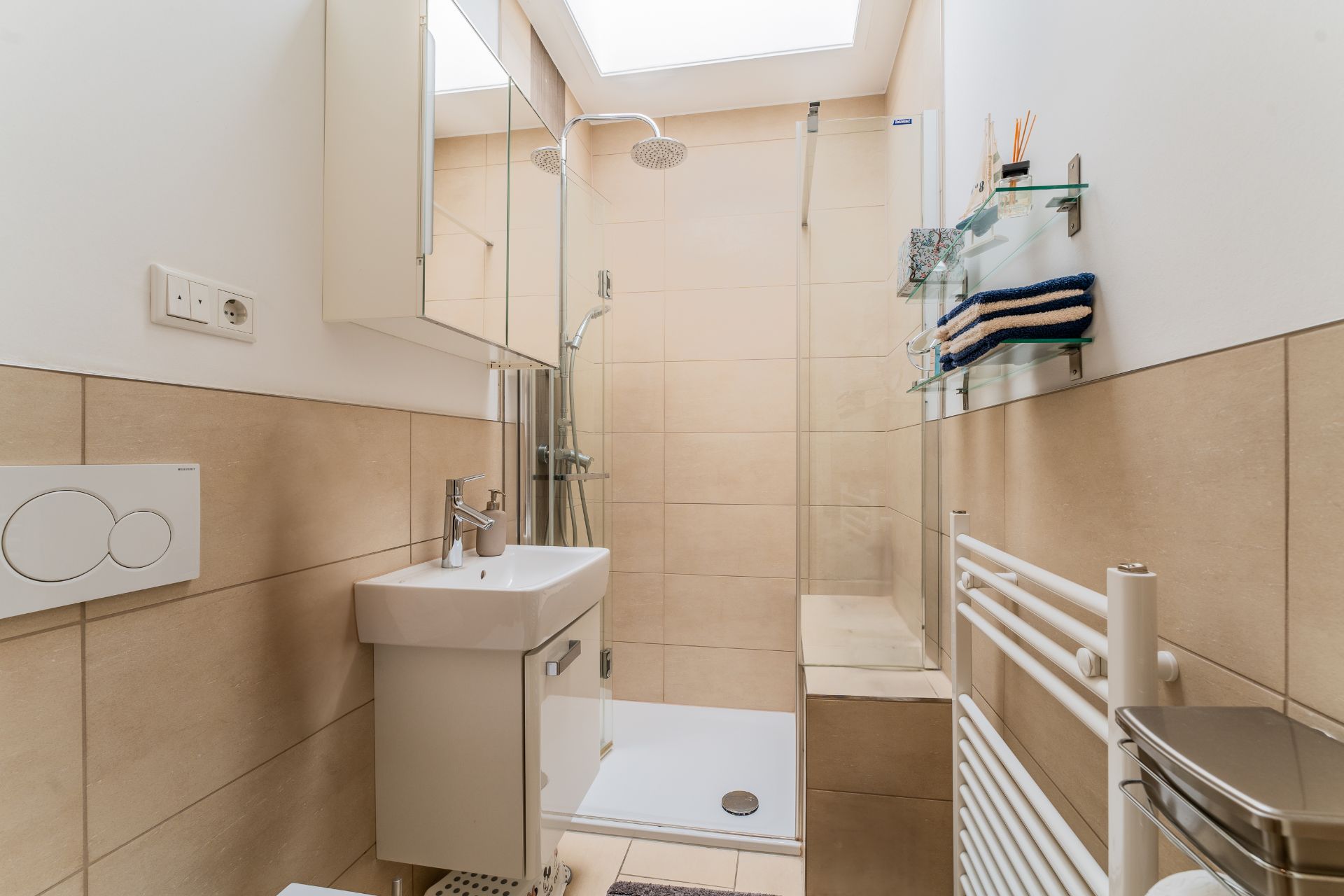 Modernes Badezimmer mit Dusche, Waschbecken, Handtuchregal und Glasablagen.
