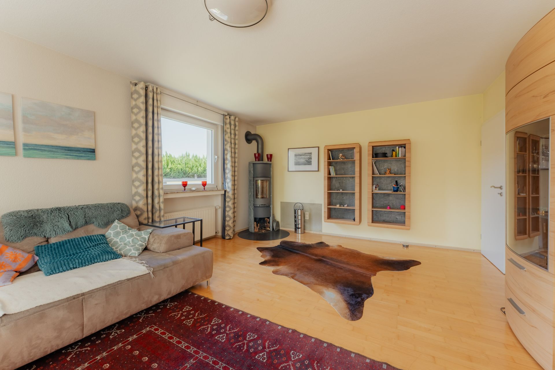 Wohnzimmer mit Sofa, Kamin, Teppich und Bücherregalen an der Wand.