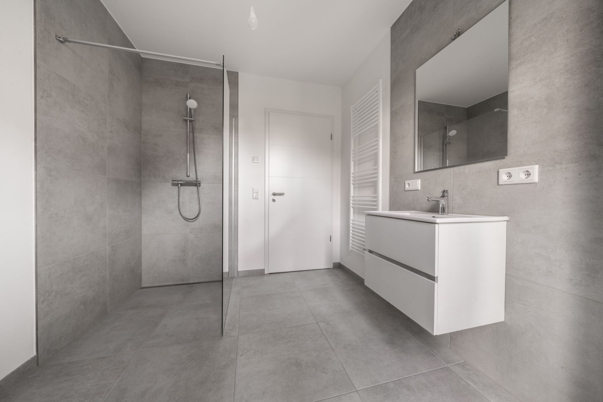 Modernes Badezimmer mit offener Dusche, Waschbecken, Spiegel und Handtuchheizkörper.