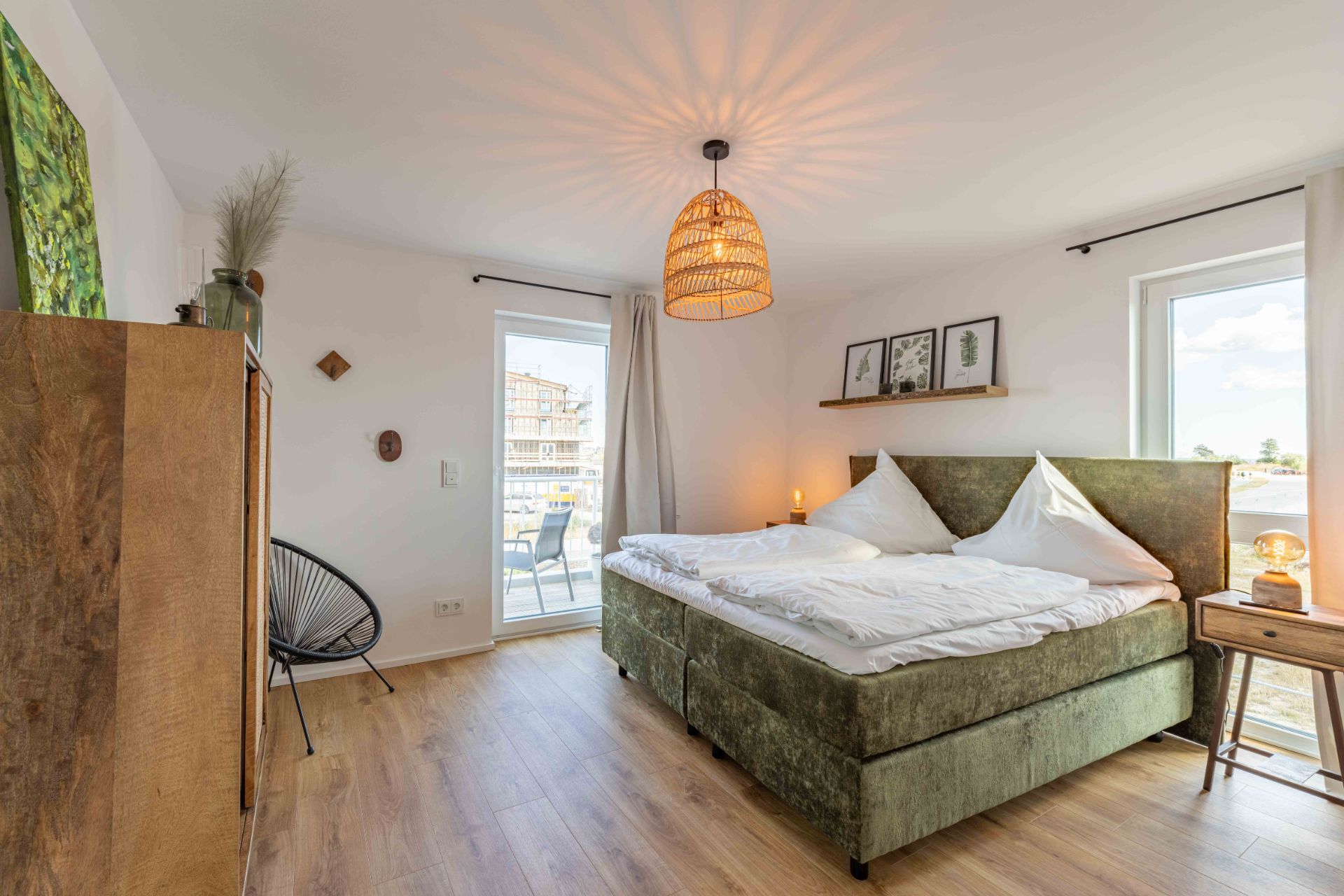 Helles Schlafzimmer mit Doppelbett, Nachttisch, Schrank und Balkonzugang.