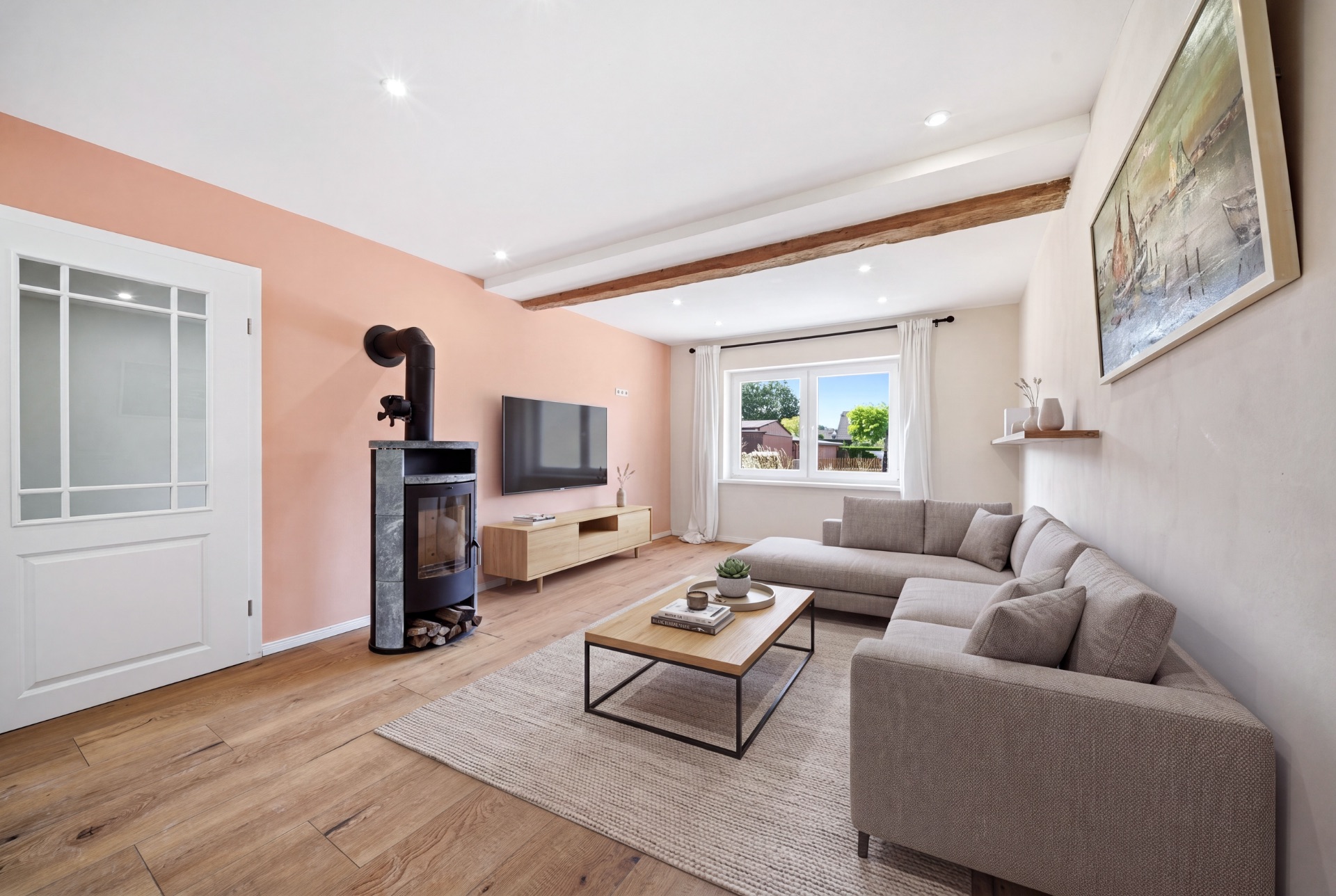 Helles Wohnzimmer mit Ecksofa, Kamin, Couchtisch und großem Fenster.