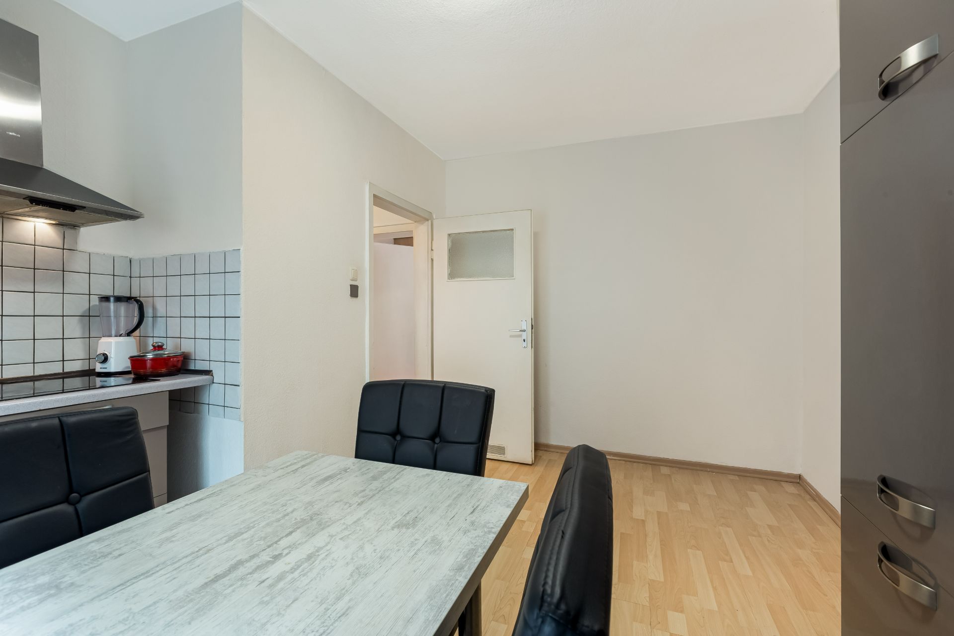 Küche mit Esstisch, vier schwarzen Stühlen und heller Holzboden sind sichtbar.