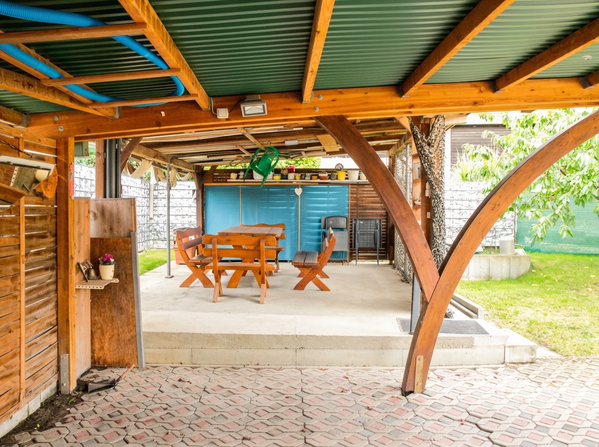 Überdachte Terrasse mit Holztisch, Bänken und Garten im Hintergrund.