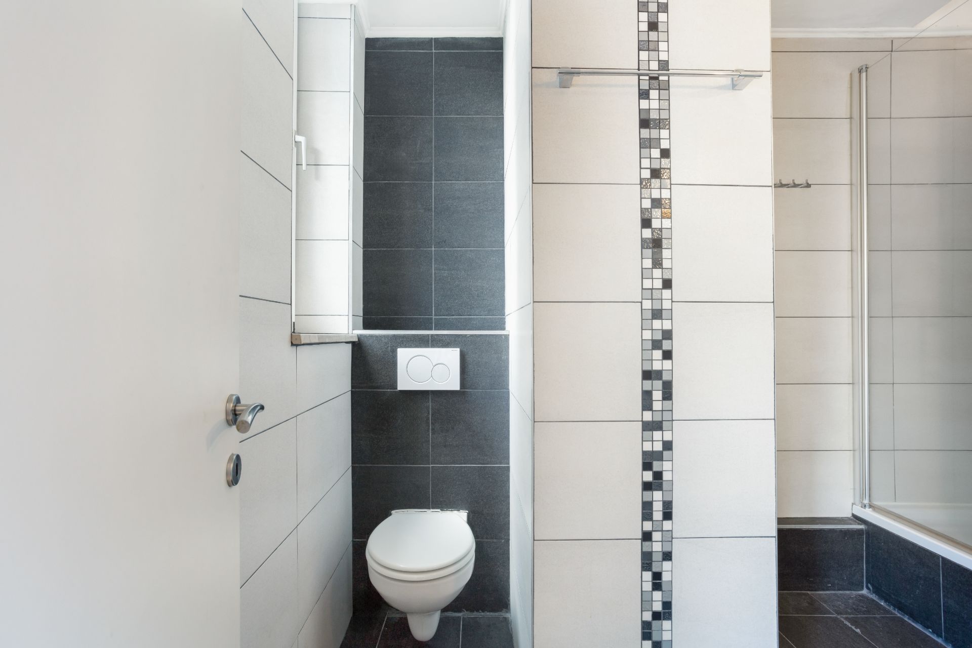 Modernes Badezimmer mit Wandtoilette, Duschkabine und Fliesen in Grau und Weiß.