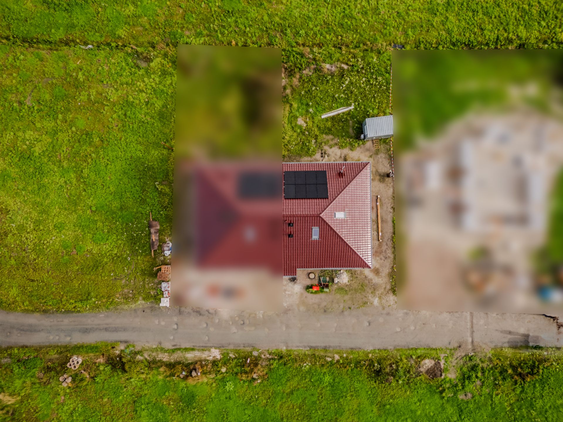 Luftaufnahme eines Hauses mit rotem Dach und Solarpanelen, umgeben von grünem Gras.