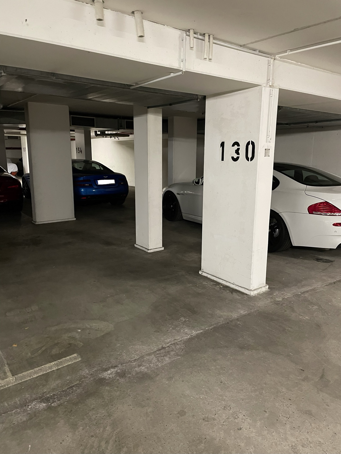Tiefgaragenstellplätze mit mehreren Autos, darunter ein weißes und ein blaues Auto. Säule mit Nummer 130.