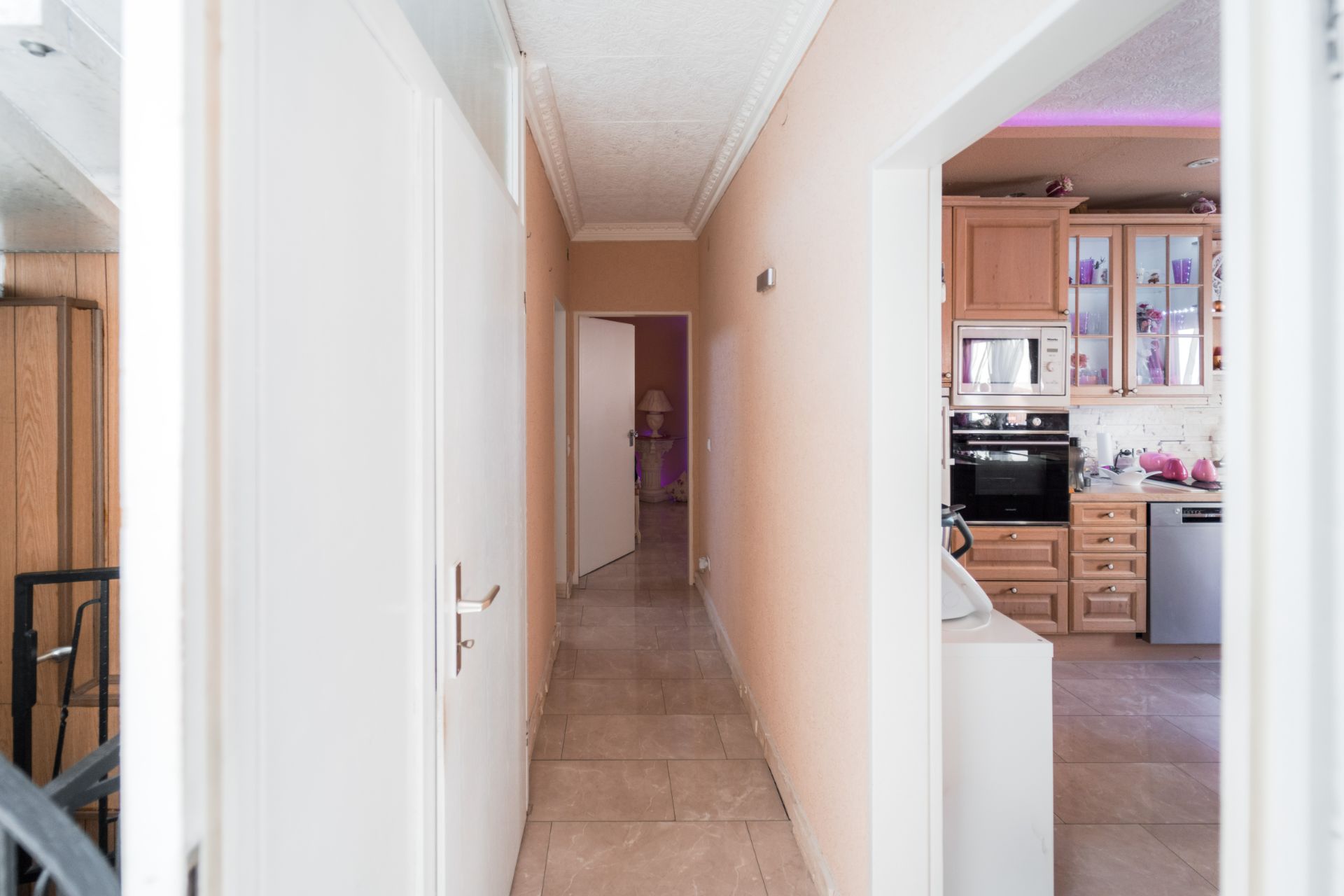 Heller Flur mit Türen, Blick in eine Küche und ein weiteres Zimmer im Hintergrund.