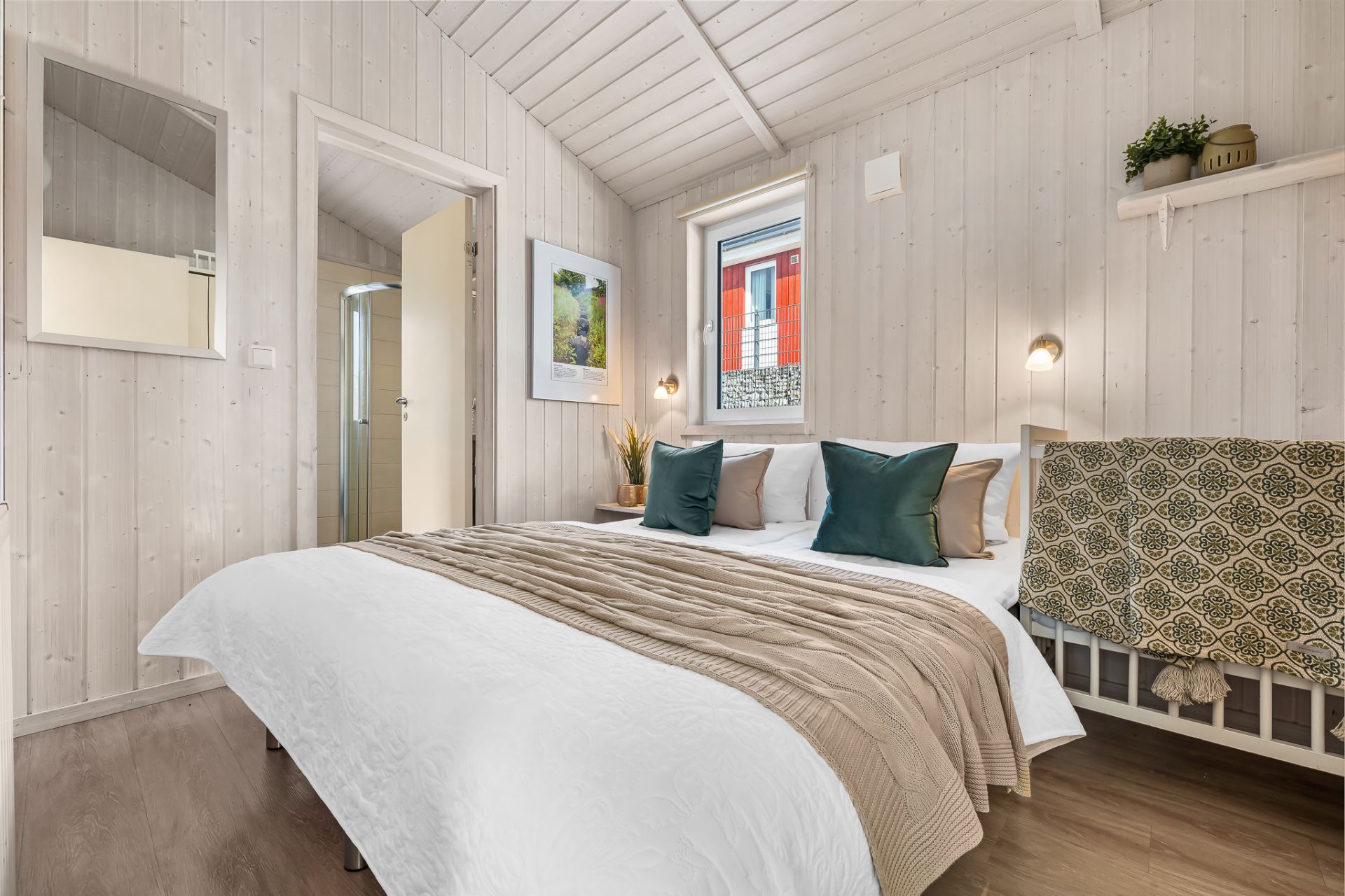 Helles Schlafzimmer mit Doppelbett, Fenster, Nachttisch und Dekoration an der Wand.