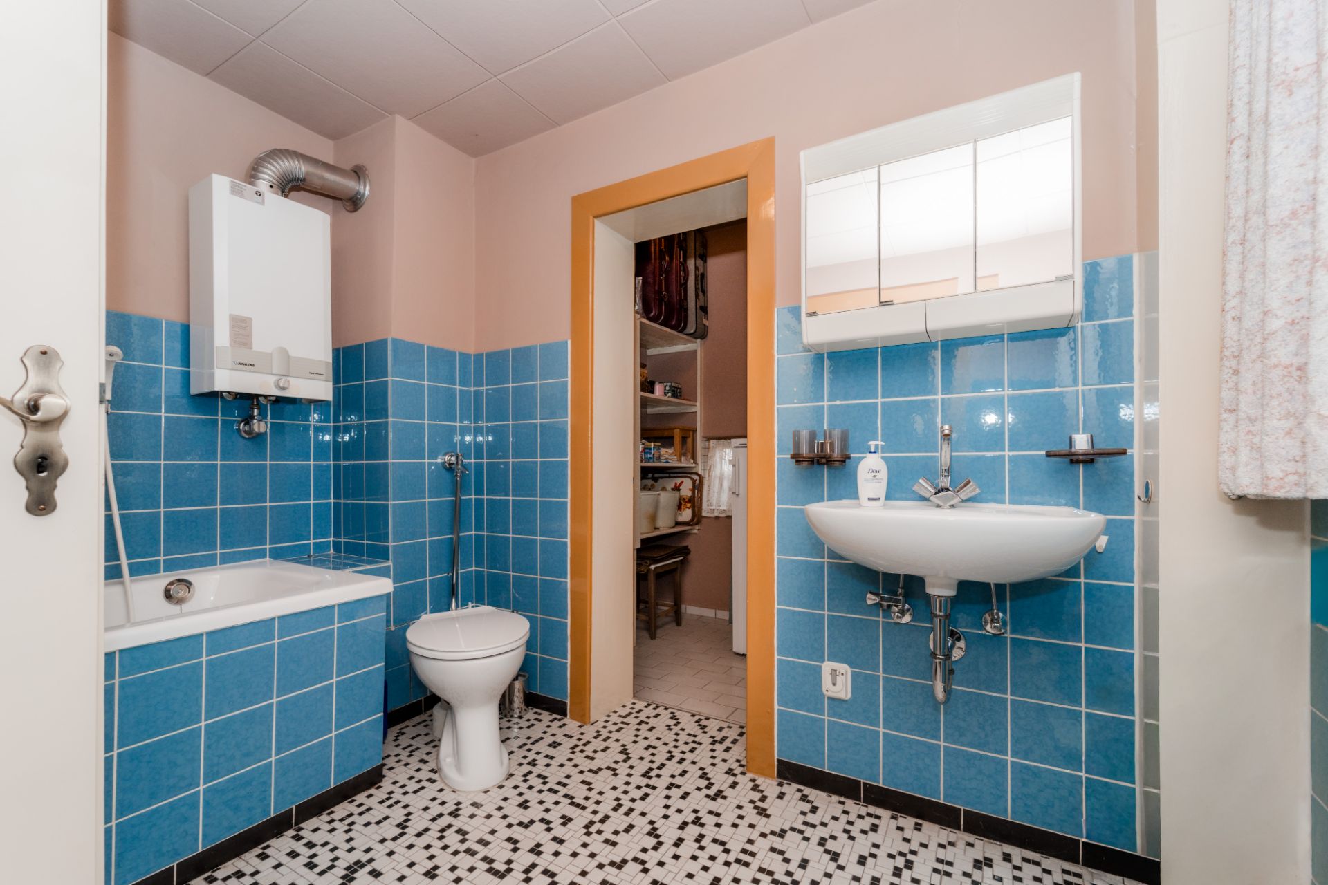 Badezimmer mit Badewanne, Toilette, Waschbecken und blauen Fliesen.