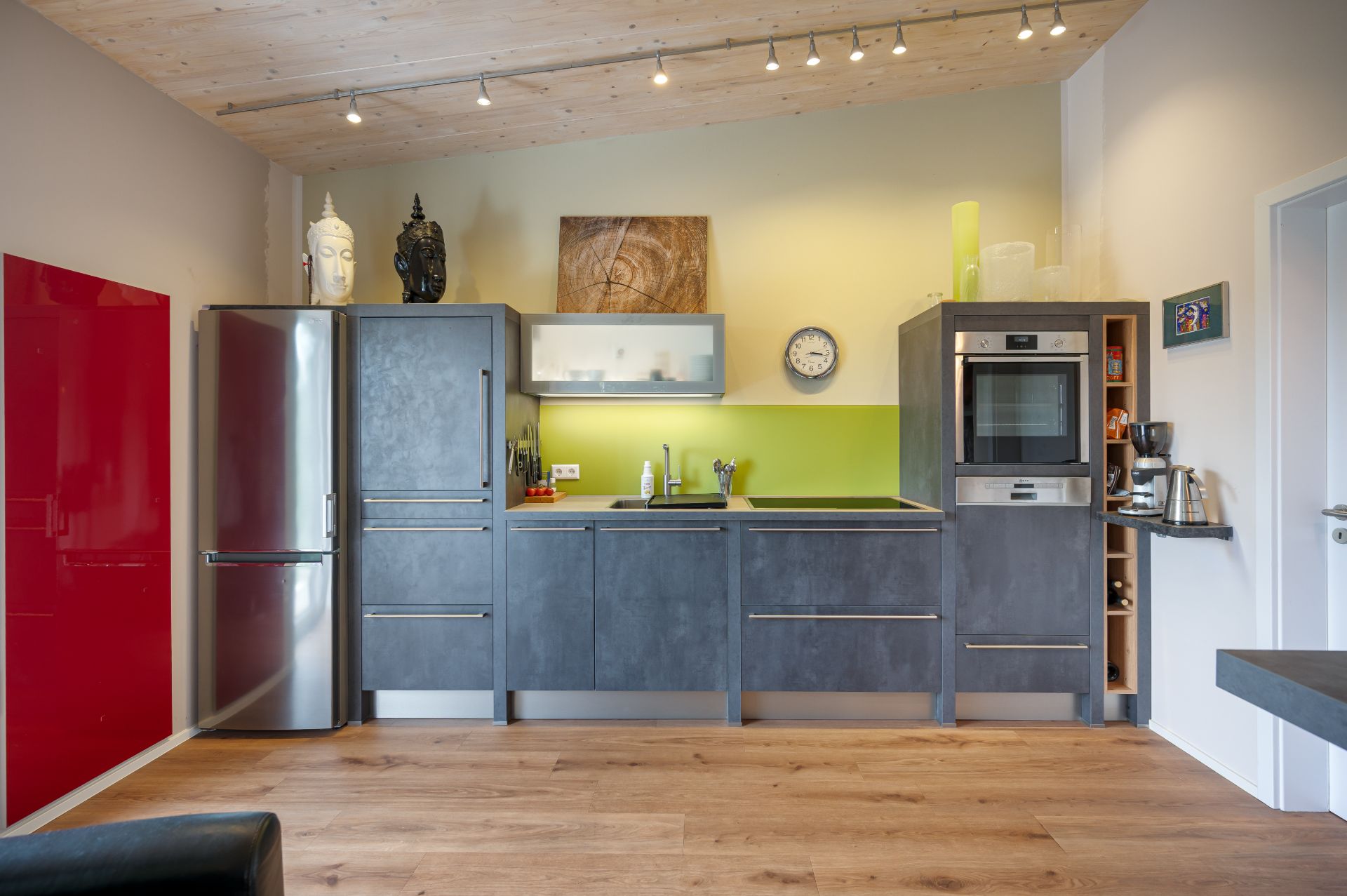 Moderne Küche mit grauen Schränken, großem Kühlschrank und grünem Wandstreifen.