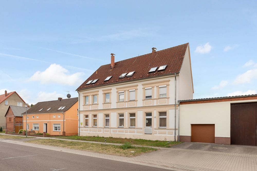Zweistöckiges Wohnhaus mit Dachfenstern und angebauter Garage an einer Straße.