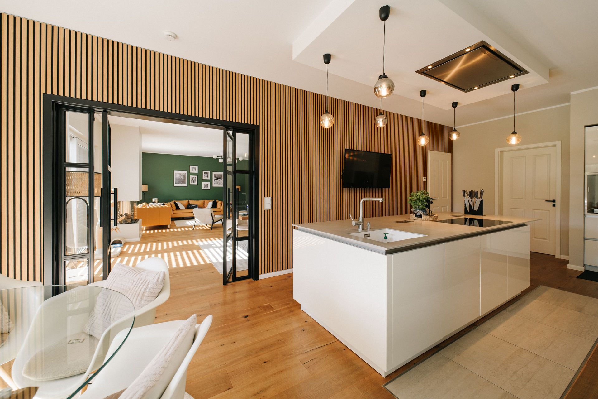 Moderne Küche mit Kochinsel, Holzfußboden und Blick ins offene Wohnzimmer.