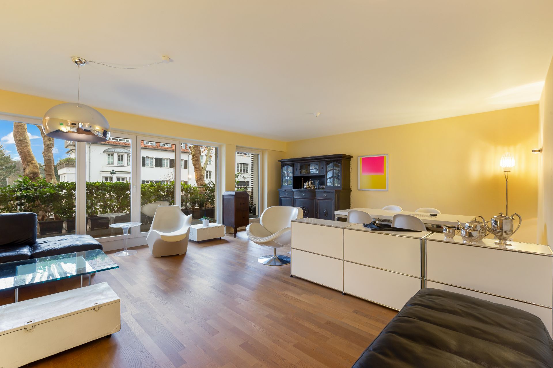 Helles Wohnzimmer mit Holzboden, modernen Möbeln, Glasfront und Zugang zu einer Terrasse.