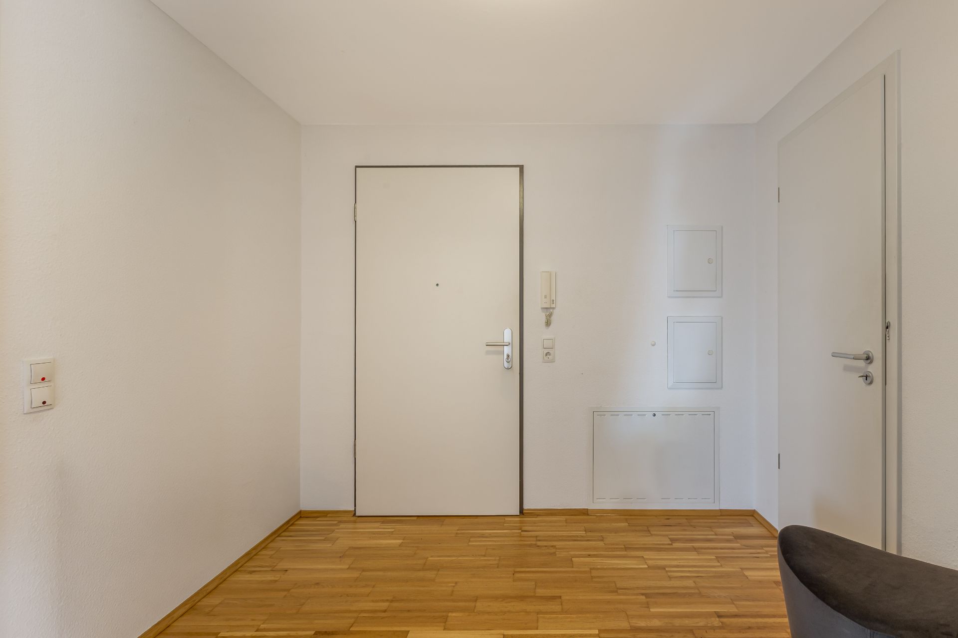 Heller Flur mit Holzboden, weißer Wand und zwei weißen Türen.