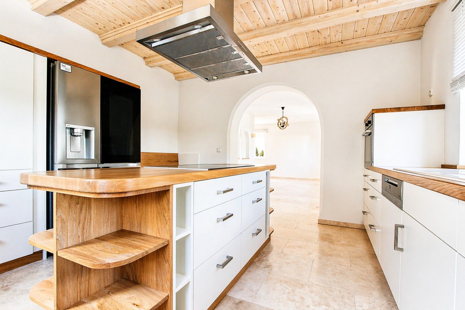Moderne Küche mit Kücheninsel, Holzdecke und großem Kühlschrank.