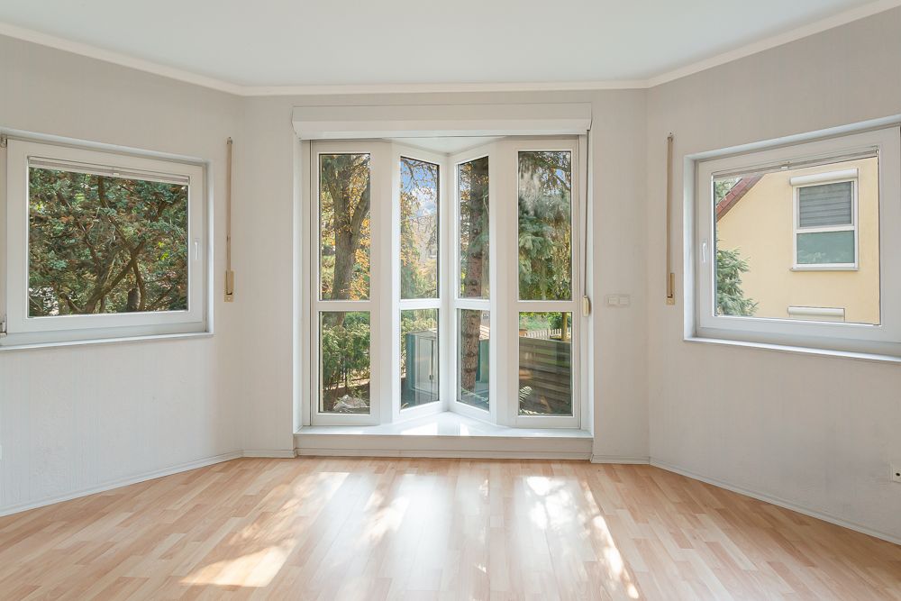 Heller Raum mit drei Fenstern und hellem Laminatboden, Blick ins Grüne.