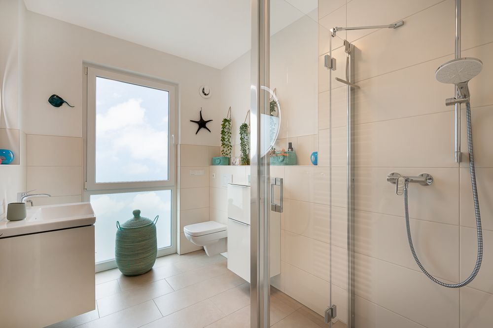 Modernes Bad mit großer Dusche, Waschbecken, WC, Fenster und dekorativen Elementen.