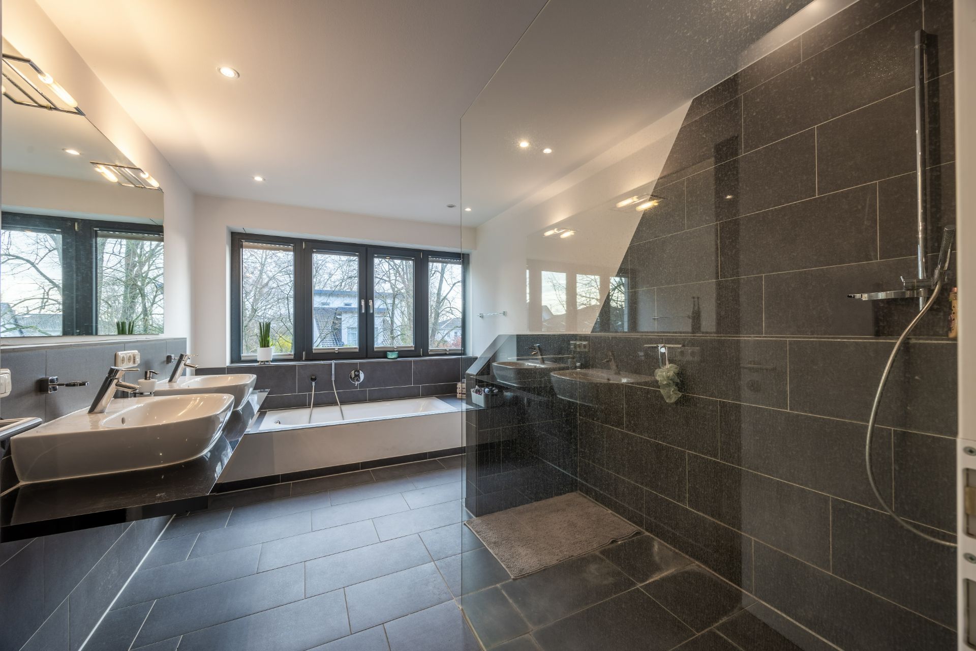 Modernes Badezimmer mit zwei Waschbecken, Badewanne und großer bodentiefer Dusche.