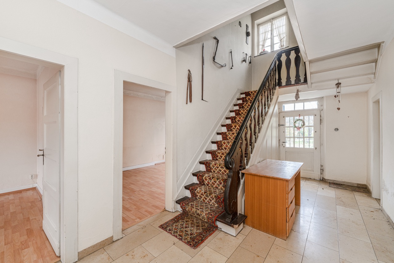 Flur mit Treppe, Teppichläufer, Holztisch und Türen zu weiteren Zimmern.