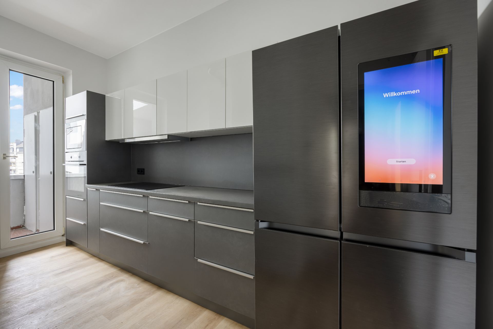 Moderne Küche mit großen grauen Schränken und Kühlschrank mit Touchscreen.