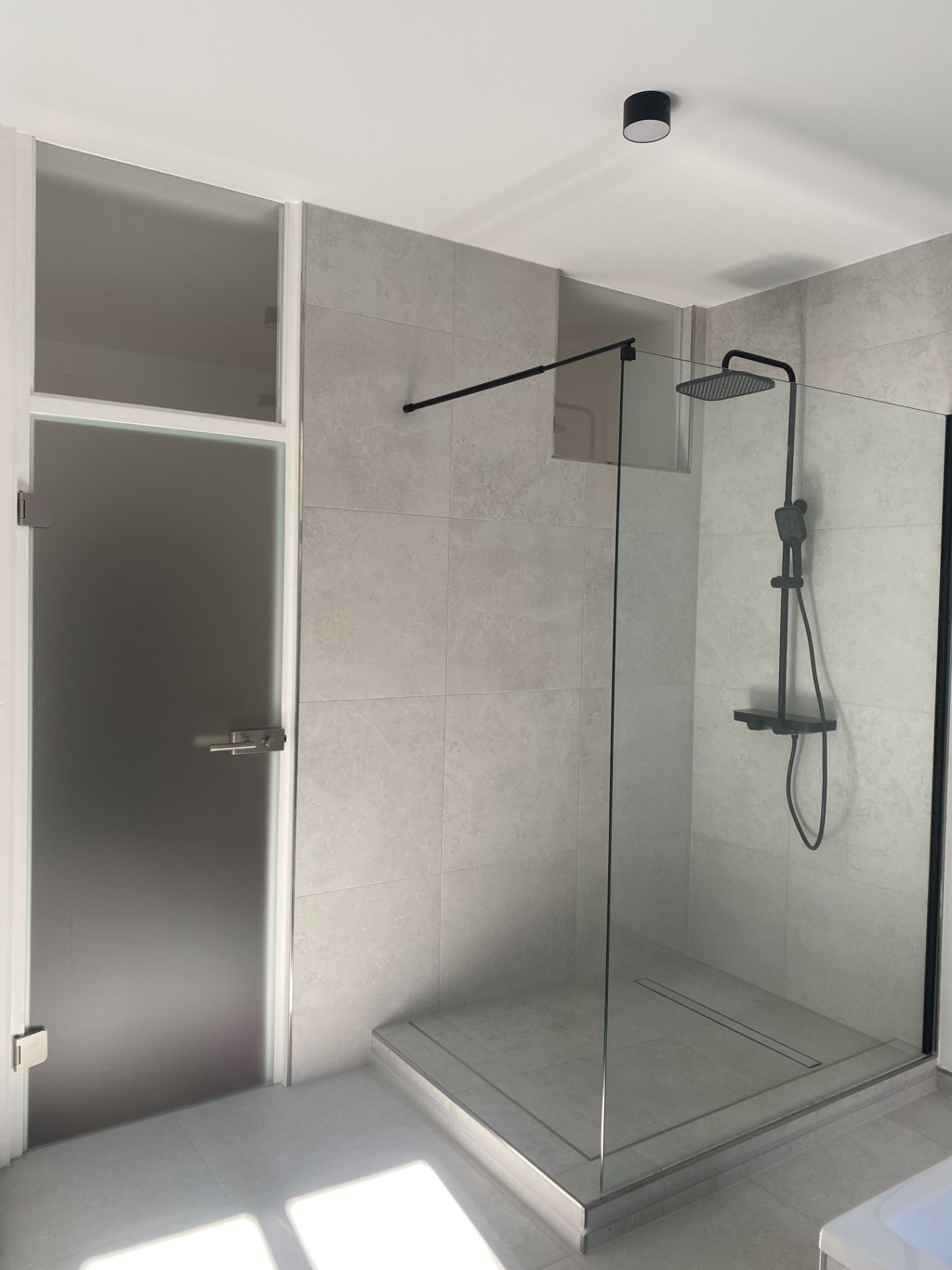Modernes Badezimmer mit begehbarer Dusche und Milchglastür.