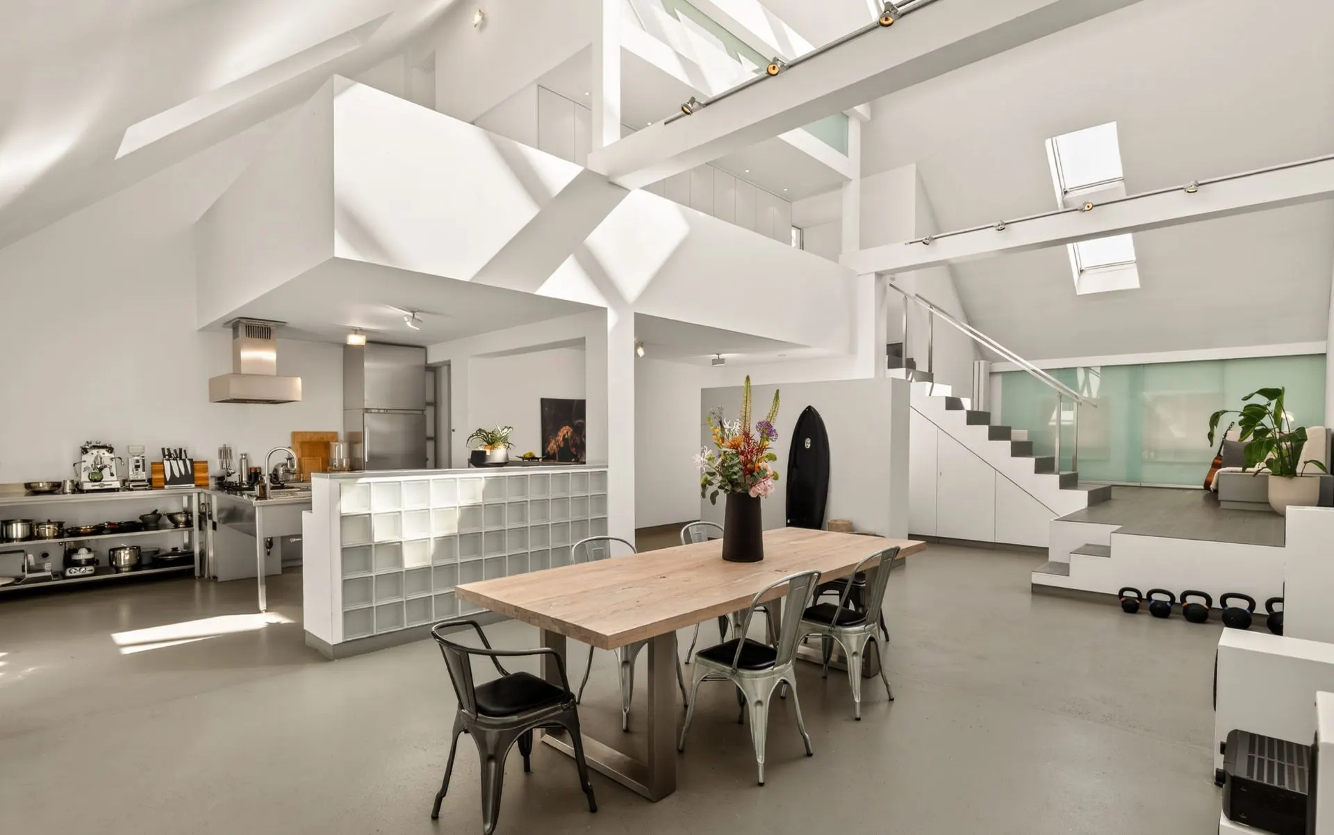 Heller, moderner Wohnraum mit Esstisch, offener Küche und Treppe zum Obergeschoss.