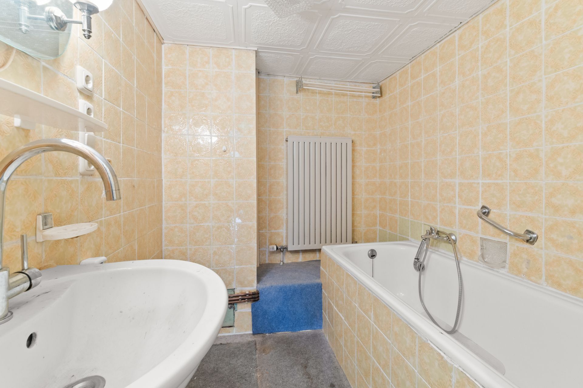Badezimmer mit Waschbecken, Badewanne und gelben Fliesen an den Wänden.