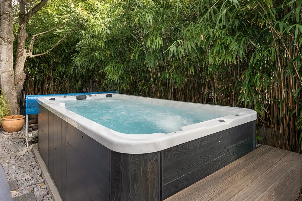 Ein Whirlpool im Garten, umgeben von Bambus und Bäumen.