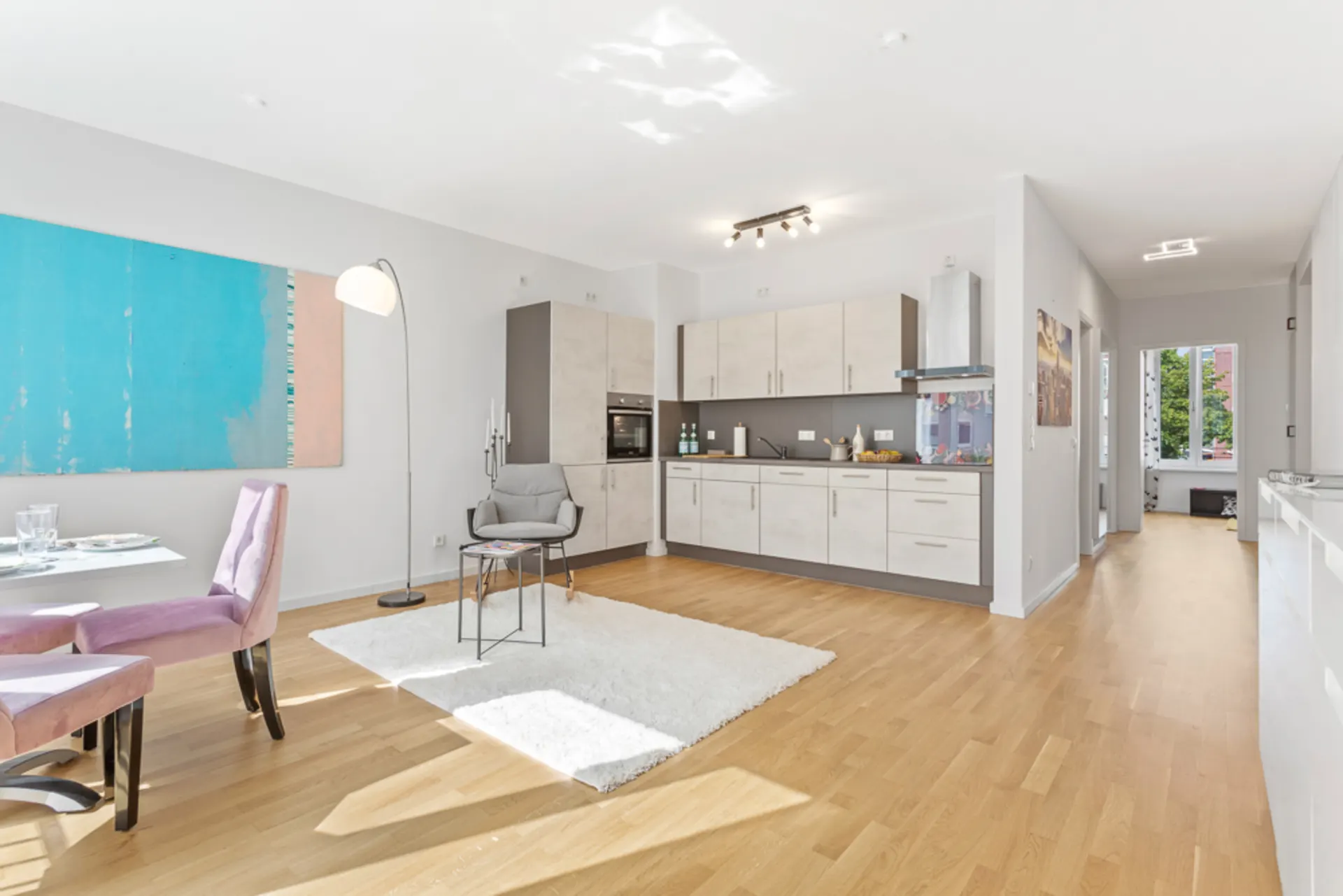 Helle offene Wohnküche mit Essbereich, Sofa, Teppich und Holzfußboden.