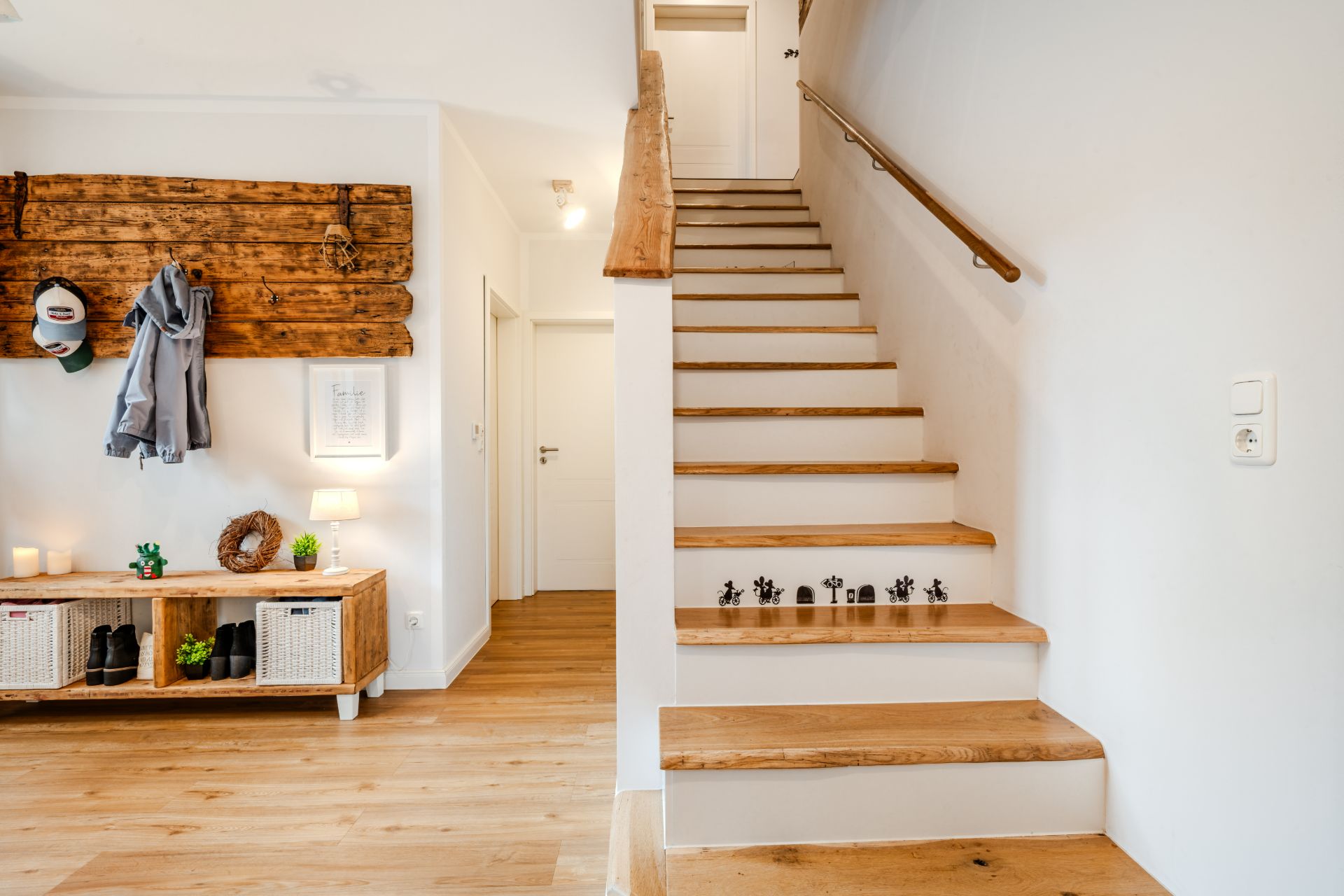 Flur mit Holztreppe, Garderobe, kleinem Regal und Holzboden.